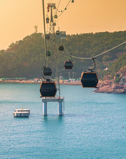 Haeundae Cable Cars gently advance over the ocean during a warm sunset in Busan South Korea