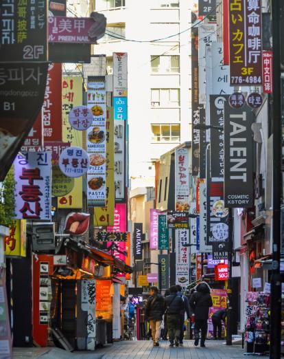 Crowds walk through bright vertical billboards in Seoul's busy and popular Myeongdong District in South Korea