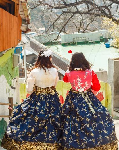 Two women walk side by side in traditional hanbok dresses in Jeonju, South Korea