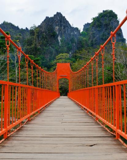 Red foot bridge with dramatic mountain scenery in background