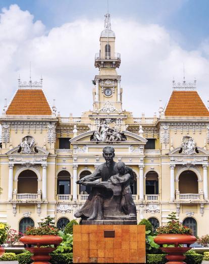 Statue in front of colonial building with Vietnamese flag in Ho Chi Minh City, Vietnam