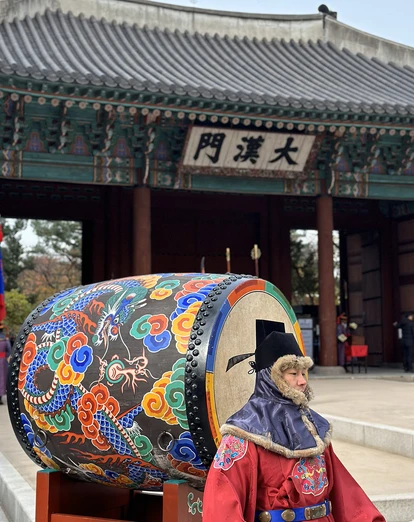 Man in traditional dress with colourful drum at temple in Seoul 
