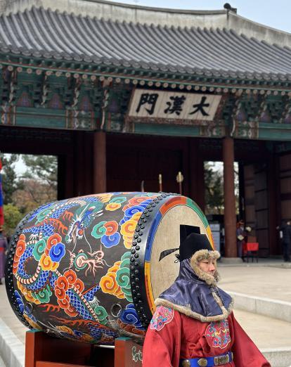 Man in traditional dress with colourful drum at temple in Seoul 