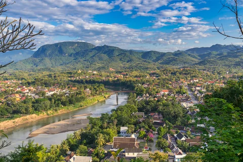 Aerial view of beautiful Luang Prabang city surrounded by jungle and sprawling alongside Nam Khan River