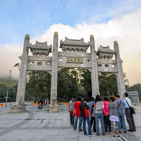 Group of people gathered in front of ornate entrance gate to Po Lin Monastery