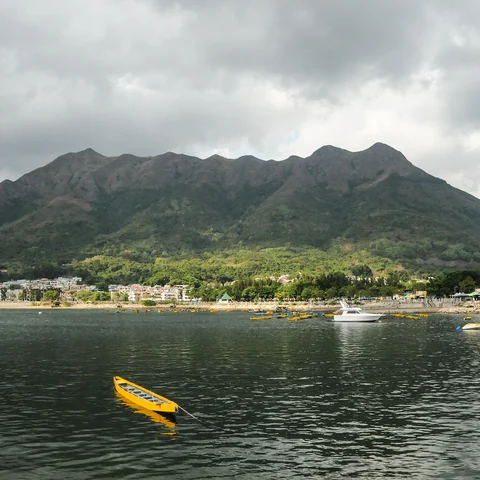 Yellow kayak in sea in front of beach and mountains in New Territories 