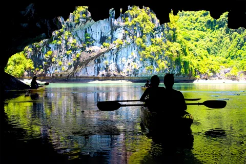 Silhouettes kayaking in Lan Ha Bay, with amazing karst rock background