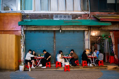 Locals eating traditional street food outside in Korea on red stools