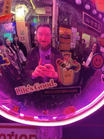 A tourist in the Euljiro Neon street in South Korea taking a selfie in a reflective surface on a Korean Wave itinerary