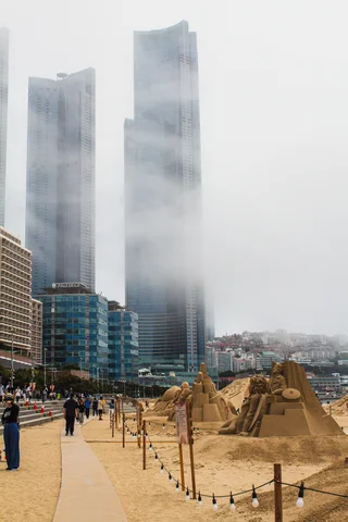 View of Busan beach with sand sculptures with the mist concealing high rise buildings