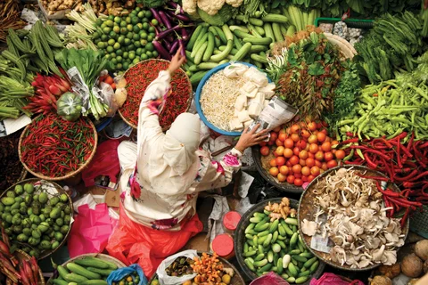 A women amongst colourful fresh fruit and vegetables in Kuala Lumpur Kota Baru market