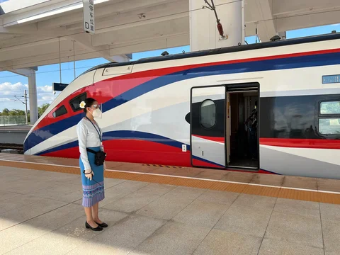 A Laotian train conductor waiting on a platform in front of a train, taken on a Laos by Rail itinerary