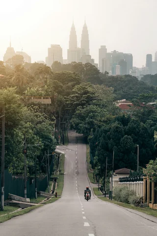 Man on a motorbike on a road in Kuala Lumpur Malaysia in front of the two towers
