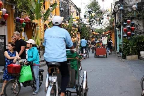 A man cycling through a lantern lined street in Hanoi