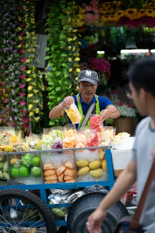 Fruit seller with cart of tropical fruits