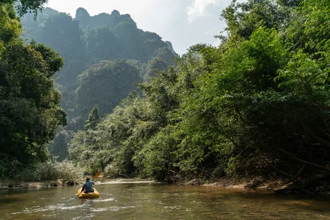 A man paddles an inflatable yellow canoe down the Sok River in Khao Sok National Park