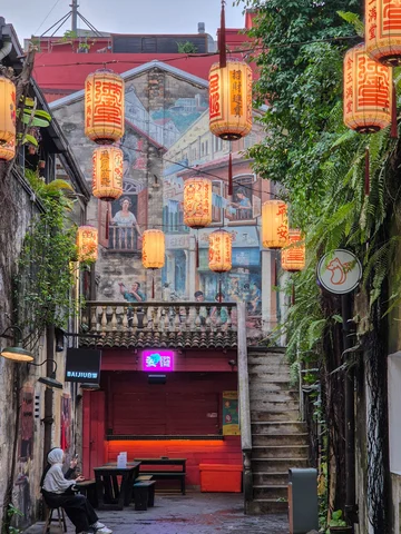 House wall with street art above a garage door. Paper lanterns are in the foreground