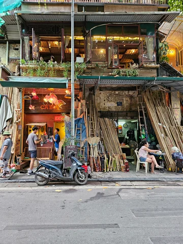 A cafe in Hanoi on the second floor, with a woodshop on the ground floor. The road outside is visible with a motorbike parked in front