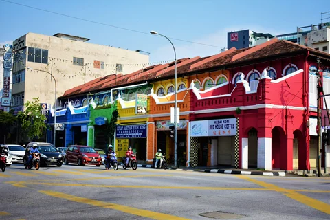 A row of shophouses, each painted a different rainbow colour