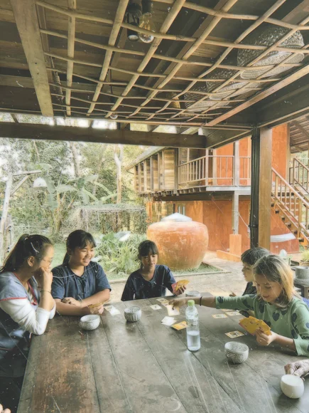 Children playing cards with locals on a homestay in Thailand