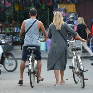 Couple pushing bicycles across busy road in Vietnam 
