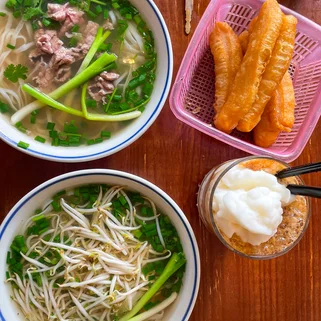 2 dishes of traditional Vietnamese bun cha with an egg coffee and fried batons next to a motorbike key in Hanoi