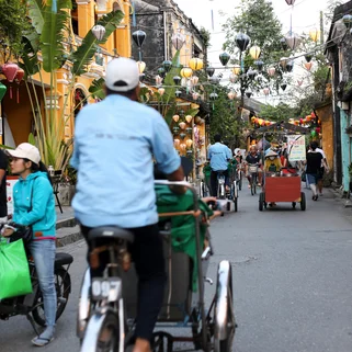 A man cycling through a lantern lined street in Hanoi