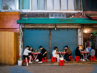 Locals eating traditional street food outside in Korea on red stools