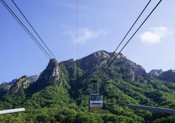 Cable car going up rocky mountains covered in tress in Seoraksan, South Korea