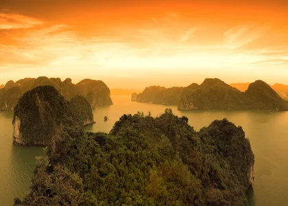 Sun sets over the dramatic limestone karst formations of Halong Bay in Vietnam
