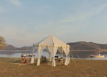 A tent with a dinner table set up by the water on a private safari experience in India in November