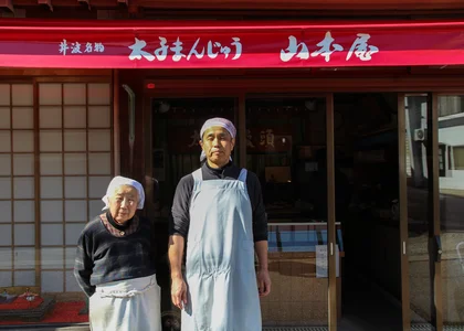 A mother and son stood in front of their family sweet shop in Japan