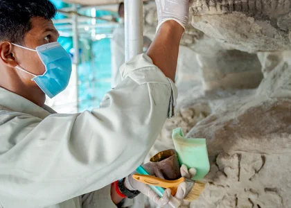 A conservation expert uses a small brush to repair a wall in the Angkor Wat temple complex