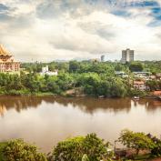 Aerial view of Kuching, with the new parliament house and other buildings strewn along the river and lined with jungle.