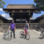 Three cyclists pausing for a photograph outside shrine