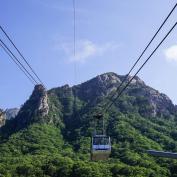 Cable car going up rocky mountains covered in tress in Seoraksan, South Korea