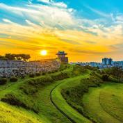 Suwon fortress walls at sunset with city skyline in background