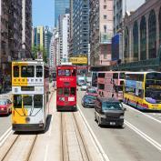 Trams and buses running alongside each other on street in Hong Kong