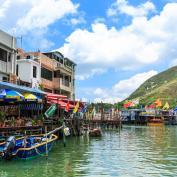 Fishing boats docked up by covered jetties alongside colourful houses