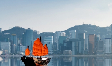 Junk boat with red flags crossing Hong Kong harbour