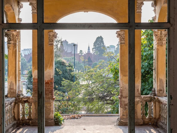 An old brick archway partially painted provides beautiful views of royal palance in Phnom Penh