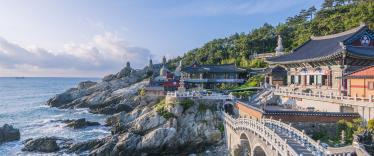 Ornate temple buildings and bridge on the coast with breaking waves 