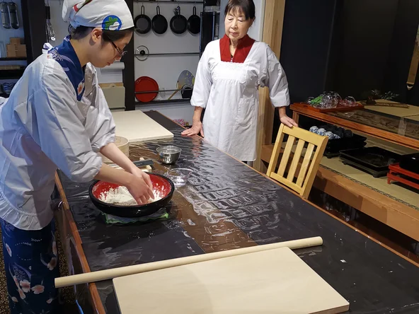Two people preparing food on kitchen table 