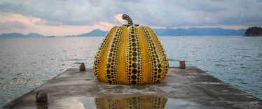 Yellow and black pumpkin sculpture on pier at Naoshima Island 