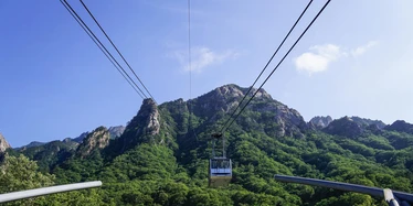 Cable car going up rocky mountains covered in tress in Seoraksan, South Korea
