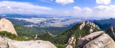 People sitting on rock in Bukhansan National Park overlooking city 