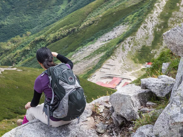 Hiker rests sat down on a rock ledge while staring at the mountainous scenery around the Kamikochi area