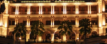Heritage building lit up at night with palm trees outside 