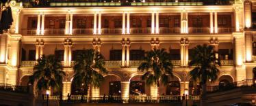 Heritage building lit up at night with palm trees outside 