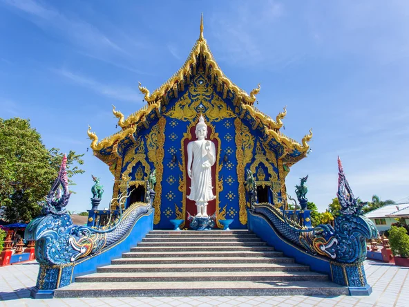 Blue Temple with white Buddha statue at top of stairs 